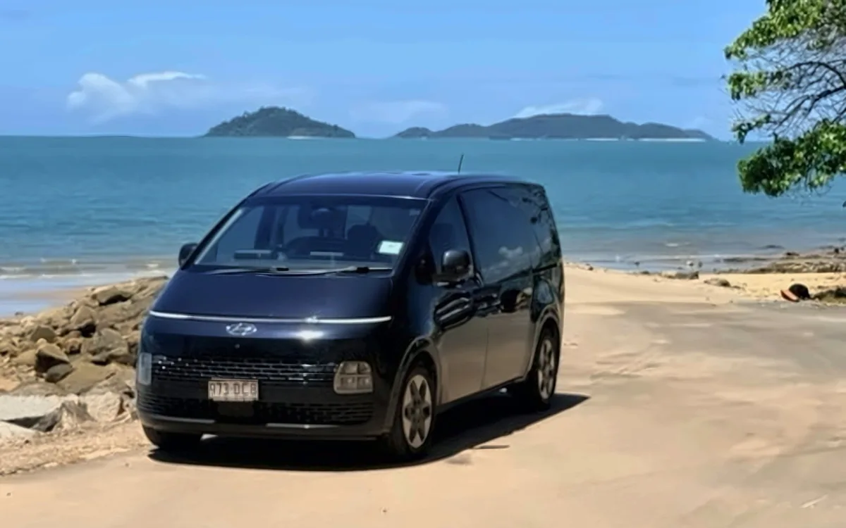 Black Hyundai Staria people mover parked by the beach near Cairns